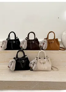 Multiple colors of vintage suede tote bags with plush bunny charms on stone steps