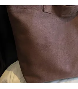 Detail view of the brown suede tote bag fabric texture with white TOTE letter printing