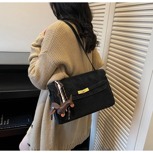 Detail of black matte tote bag featuring a golden lock and cute dog bag charm