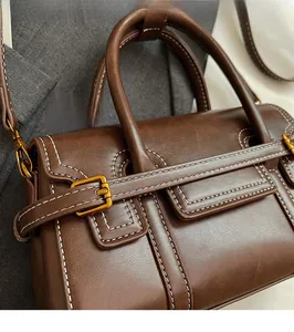 Detailed view of deep brown leather handbag featuring contrast stitching and brass buckle