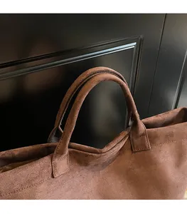 Close-up of durable brown suede tote bag handles with precise stitching and soft texture