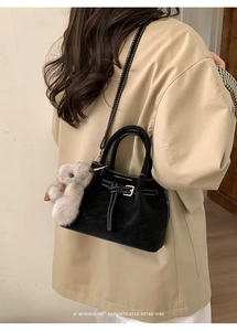 Detail of black suede tote bag featuring white contrast stitching and retro buckle accent