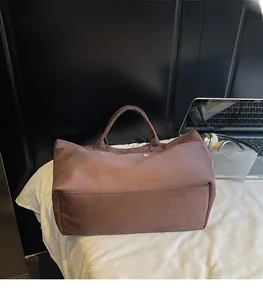 Detail of tan tote bag showing large capacity and soft texture in a lifestyle office setting