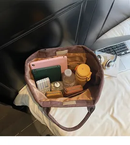 Detail view of large corduroy tote bag showing spacious interior with tablets and daily items