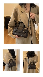 Detail of dark brown vintage handbag with white contrast stitching and gold buckle accents