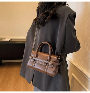 Dettaglio di una borsa vintage in pelle marrone con cuciture a contrasto e fibbie in metallo