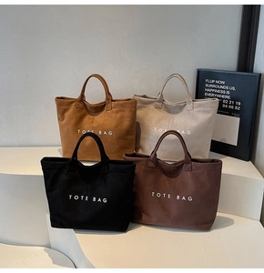 Detail view of large capacity canvas tote bags in four neutral colors with logo text