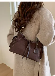 Details einer dunkelbraunen Wildleder-Schultertasche mit weißen Kontrastnähten und Quasten