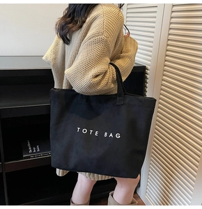 Detail showing high-capacity black canvas tote bag with white TOTE BAG lettering print