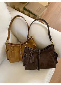 Detailaufnahme der Wildleder-Achseltaschen in Braun und Hellbraun auf einem Sofa
