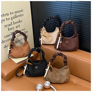 Detail of suede dumpling bags featuring ruched handles and decorative wooden beads