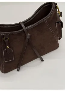 Detailed side view of dark brown suede shoulder bag with white contrast stitching