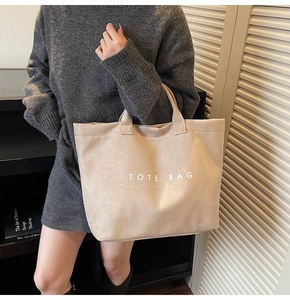 Close-up of beige suede tote bag with white TOTE BAG lettering for daily commute