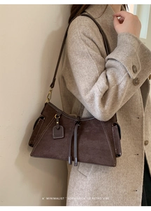 Details der braunen Wildleder-Schultertasche mit weißen Kontrastnähten und Seitentasche
