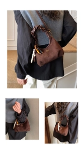 Detail of dark brown suede crescent bag with ruffled handle and boho beaded charms