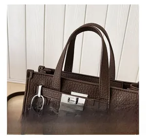 Detail view of brown lychee grain leather bag with silver buckle and faux fur charm