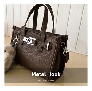 Macro detail of silver-toned metal hardware and lychee grain leather on dark brown tote