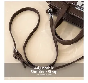 Detail of adjustable leather strap with silver metal buckle on a brown handbag