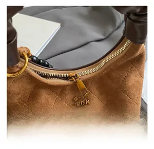 Detailed macro view of gold metal zipper and quilted leather texture on brown handbag