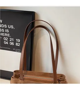 Close-up of brown leather tote bag handle and metallic zipper with retro texture