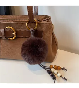 Detail of vintage brown textured handbag with fur pom-pom and wooden bead tassel