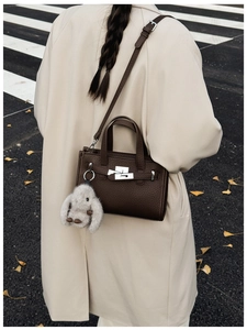 Detail of dark brown pebble leather handbag with silver lock and plush bunny charm