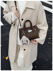 Close-up of deep brown lychee grain leather handbag with metal lock and rabbit charm