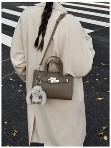 Close-up of a dark brown lychee leather handbag with a silver lock and plush rabbit charm