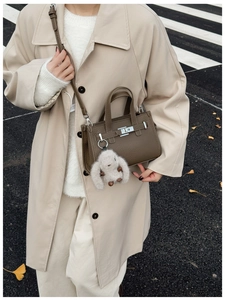 Close-up of dark brown lychee leather handbag with silver twist lock and plush charm