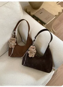 Detalle de bolsos hobo de ante en tonos marrones con colgantes de perro de peluche suave