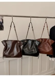 Vue détaillée de grands sacs cabas avec bandoulière chaîne en noir, marron foncé et caramel