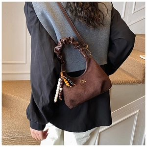 Detail of brown suede dumpling bag featuring pleated handles and colorful bead charms