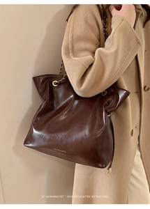 Detailed view of dark brown vintage tote bag with gold chain strap on model's shoulder
