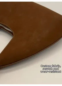 Detalle del bolso medialuna de ante marrón con tejido texturizado y costuras finas