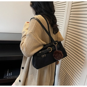 Detail of black vintage shoulder bag with golden ring hardware and plush ball charm