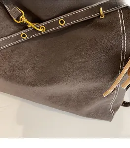 Close-up of vintage brown leather tote bag with white stitching and gold hardware