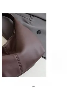 Close-up of deep brown leather tote bag with lychee texture and silver zipper detail