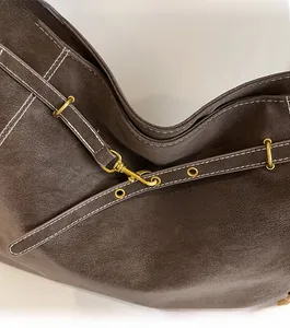 Detail of vintage bronze hardware and contrast stitching on dark brown leather tote bag