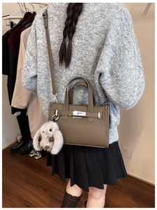 Detail of dark brown pebbled leather tote with metal turn-lock and plush bunny charm
