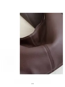 Close-up of brown pebbled leather texture and precise double stitching on cross-body bag