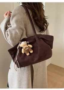 Detail view of large dark brown suede tote bag featuring a cute teddy bear charm
