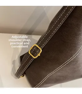 Detail of adjustable brown leather strap with contrast white stitching and gold buckle