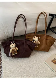 Close-up of velvet tote bags in dark coffee and caramel with bear charms on a cozy bed
