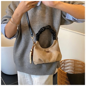 Detail of beige quilted suede bag with black ruched handle and vintage beaded charm