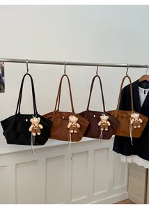 Detail view of four suede tote bags in black, brown, and coffee with cute bear charms