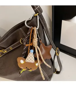 Close-up of plush bear and leather star charms on a large shoulder bag with heart clasp