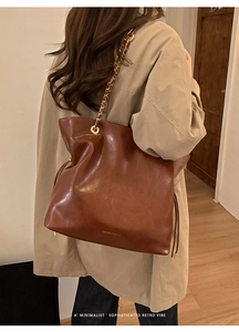 Close-up of brown vintage tote bag with gold chain strap and drawstring details