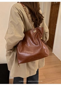Détail d'un cabas en cuir marron foncé avec chaîne dorée et finition rétro sophistiquée