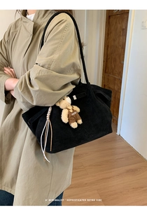 Detail of black corduroy tote bag with vertical texture and cute bear charm