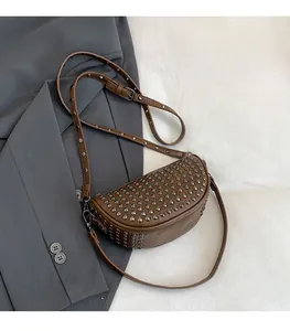Detail view of dark brown leather crossbody bag with silver rivet studs and adjustable strap
